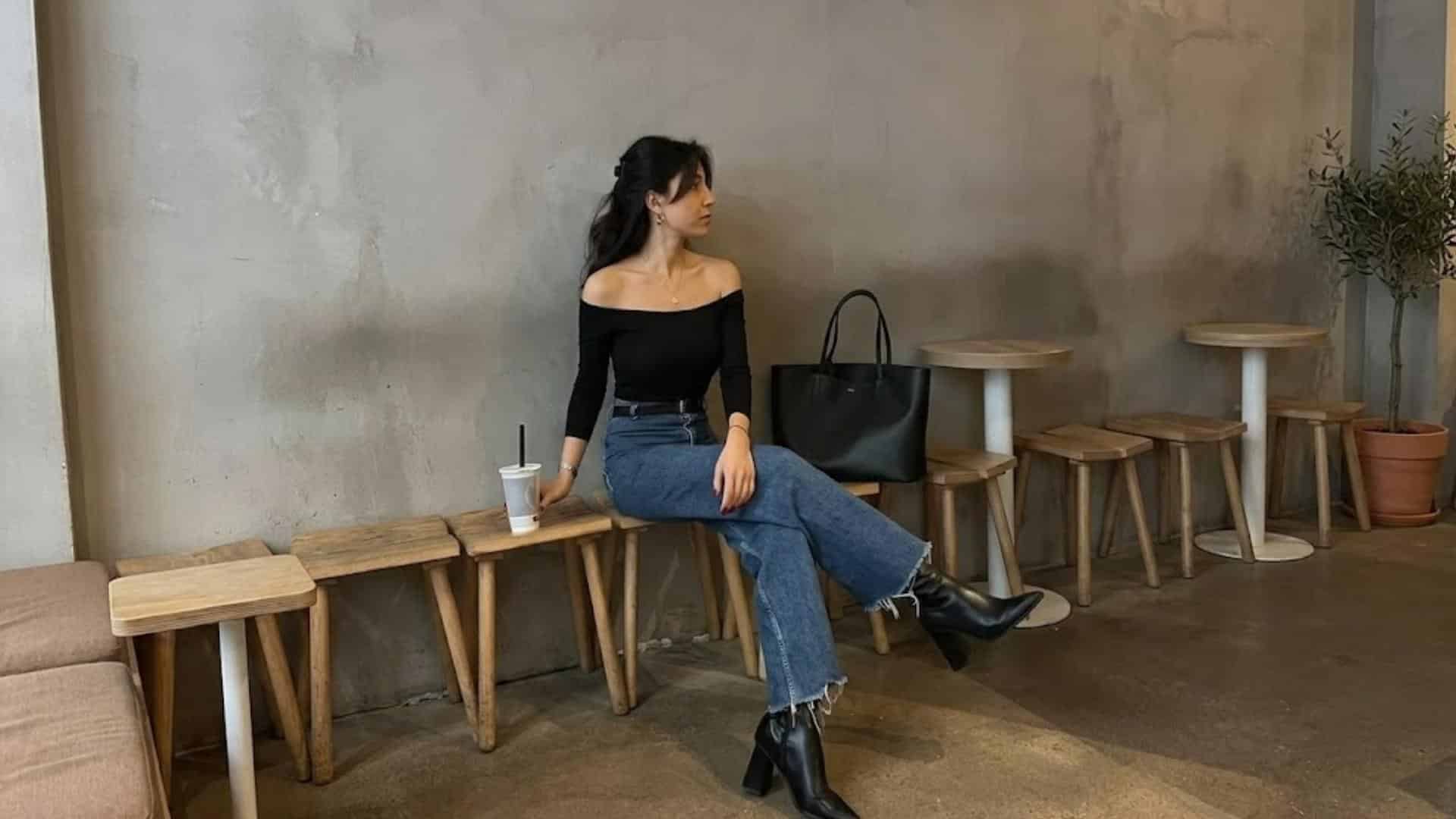 Woman wearing an off shoulder black top with high waist jeans and ankle boots for a stylish casual date outfit