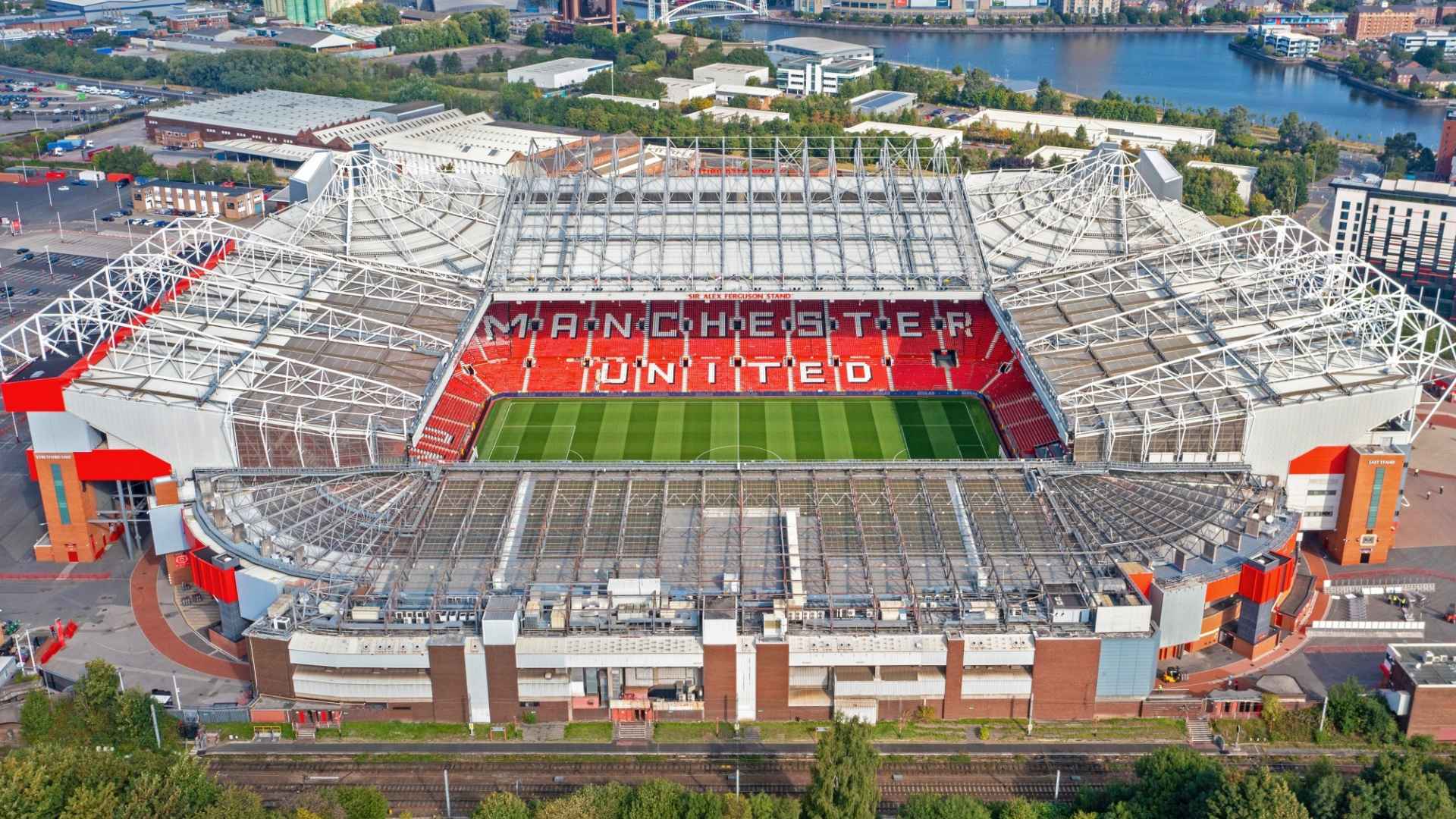 Aerial view of Old Trafford stadium showing the pitch, stands, seating areas, and surrounding structures from above.