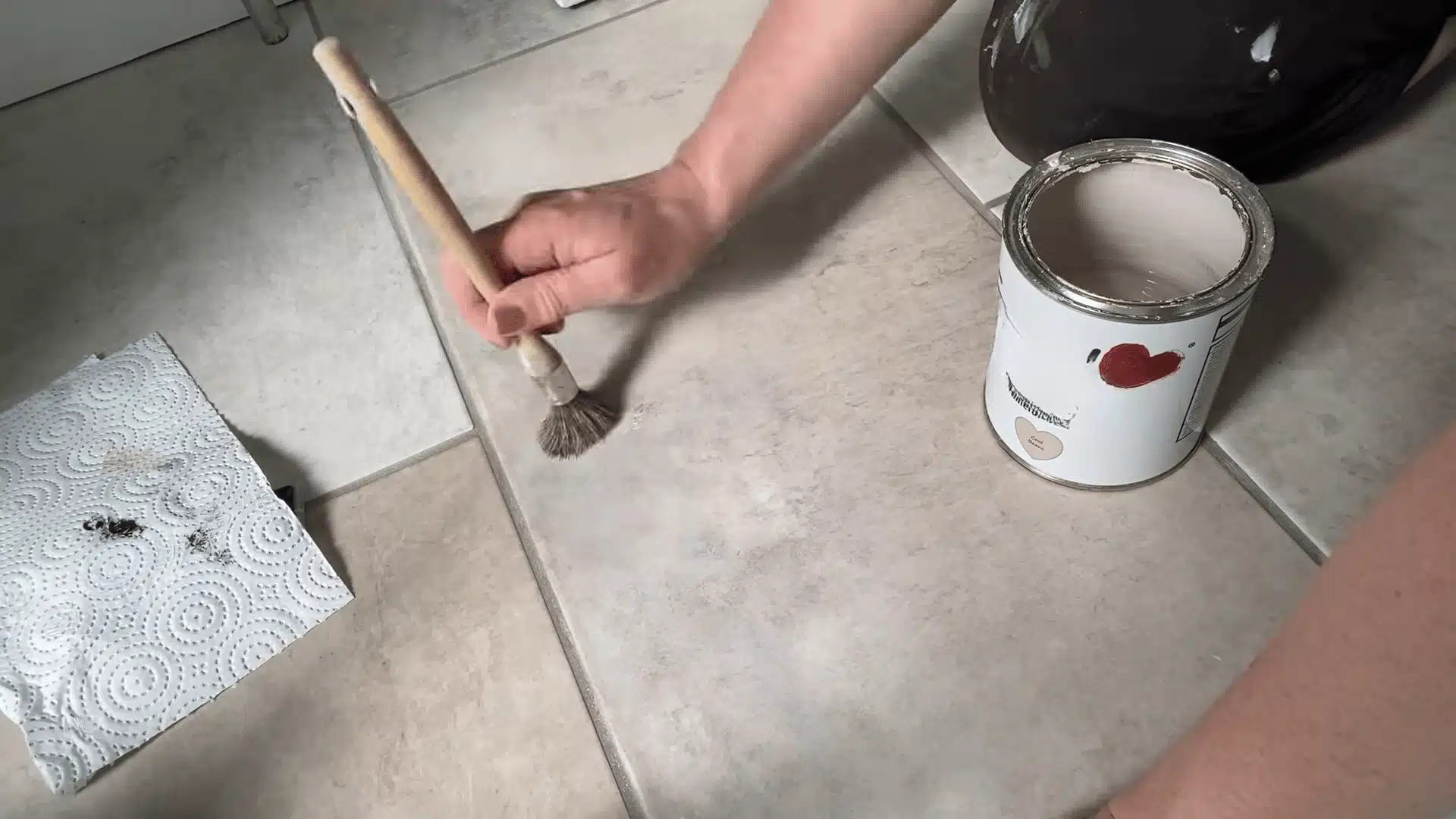 Painting a repaired tile area with a small brush to match the original finish