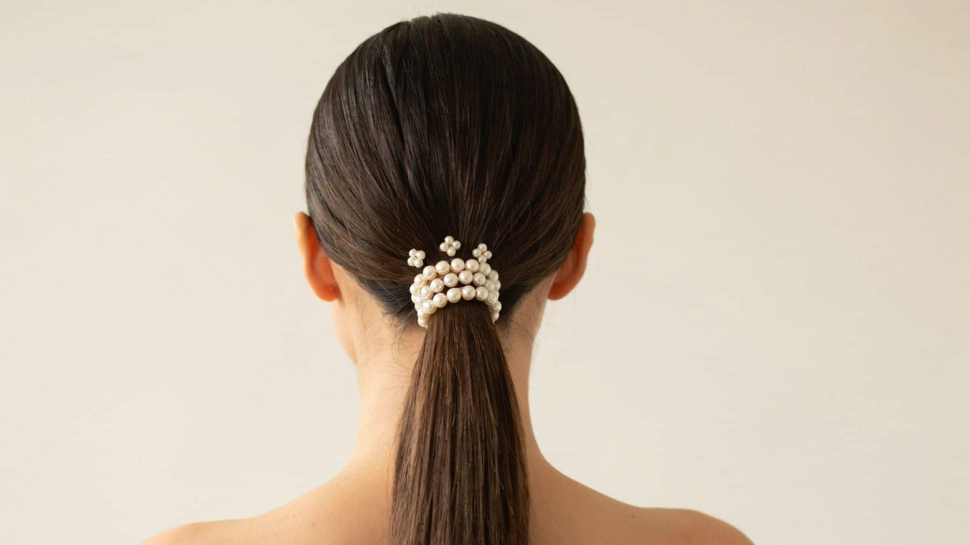 Sleek low ponytail secured with a pearl-embellished hair clip