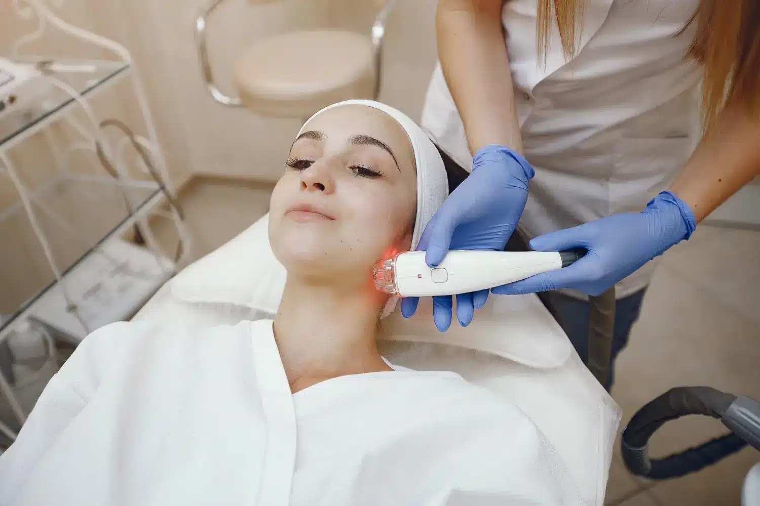 Woman receiving facial treatment with a handheld device in a spa setting