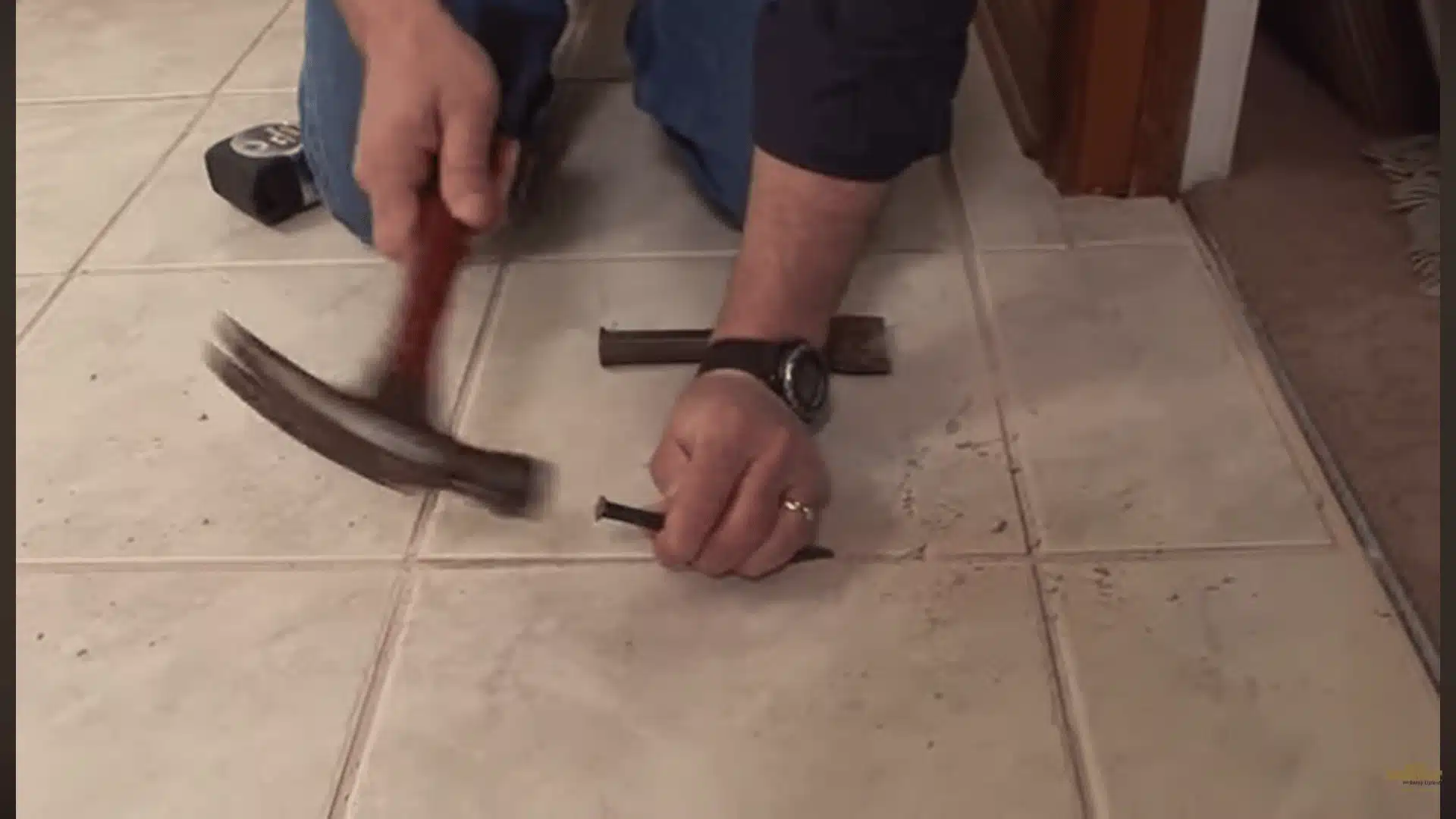 Removing grout around a broken ceramic tile before lifting it from the floor with a chisel.