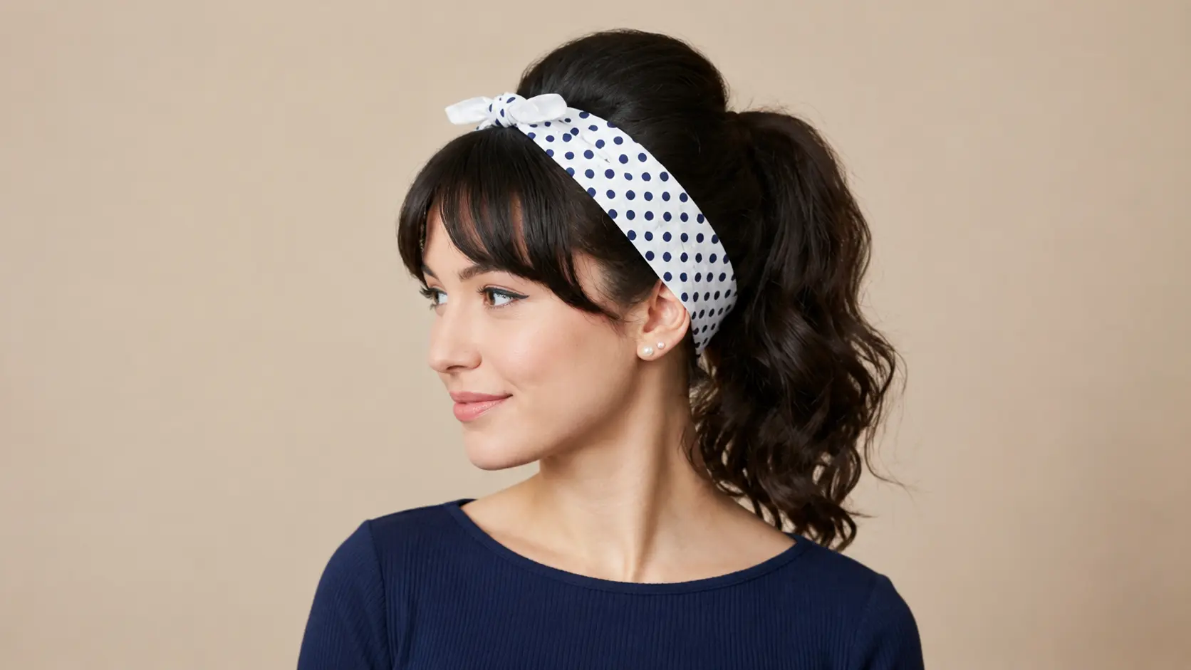 Retro ponytail hairstyle with a teased crown, voluminous waves, and a polka dot headband accessory.