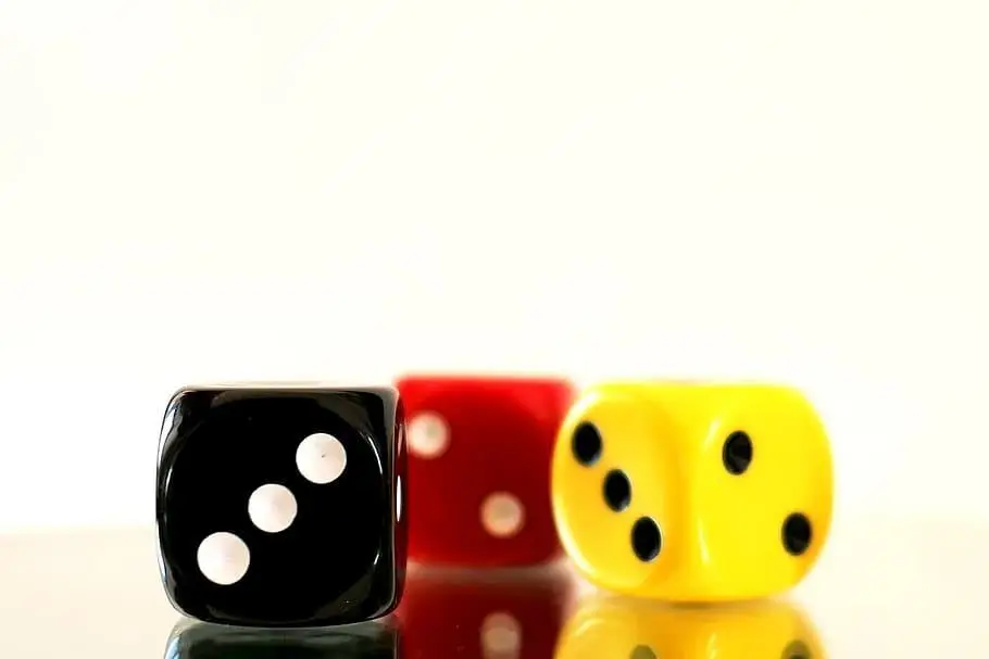 Black, red, and yellow dice on reflective surface with bright background