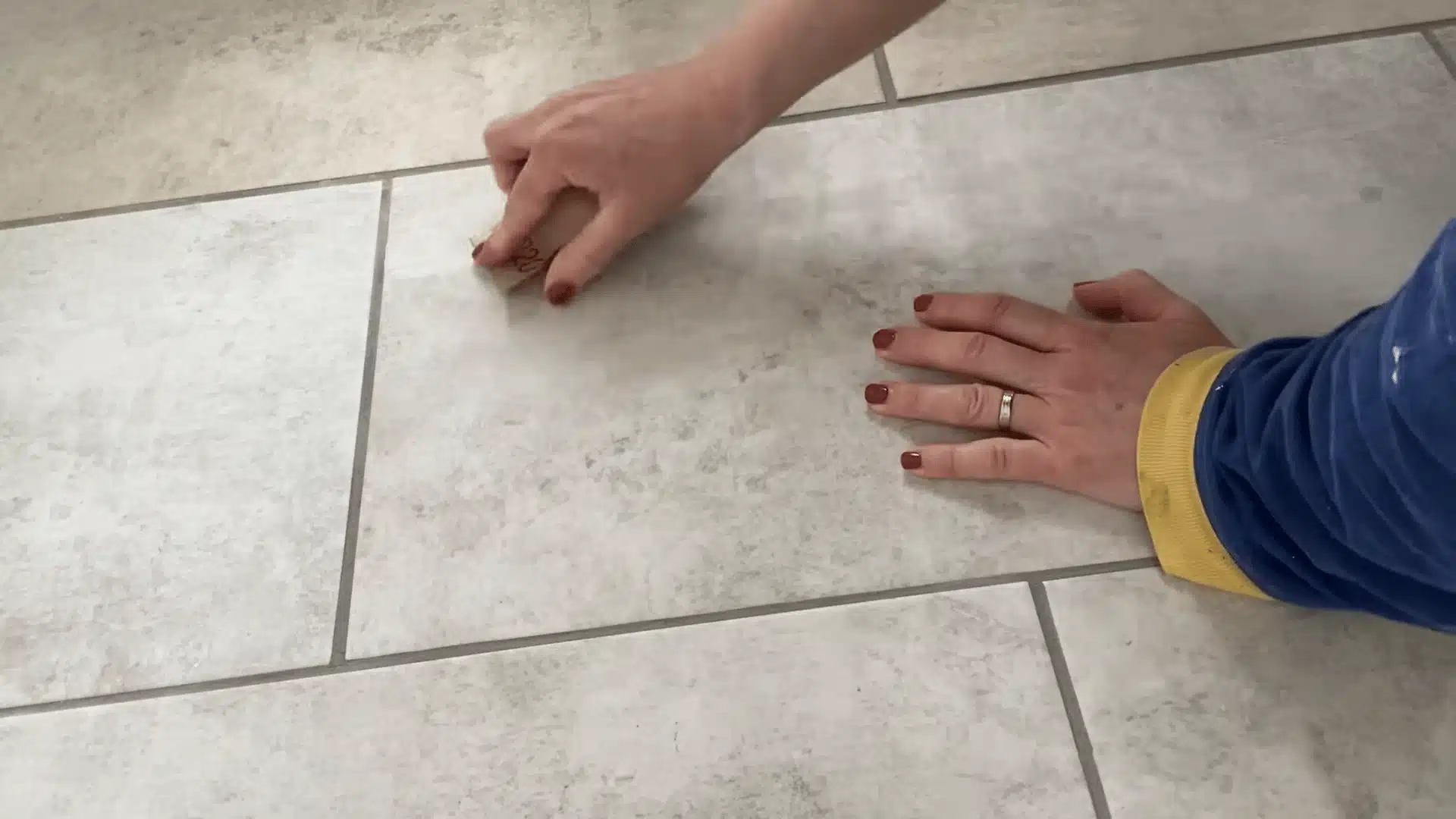 Sanding a filled crack on a tile surface to create a smooth finish