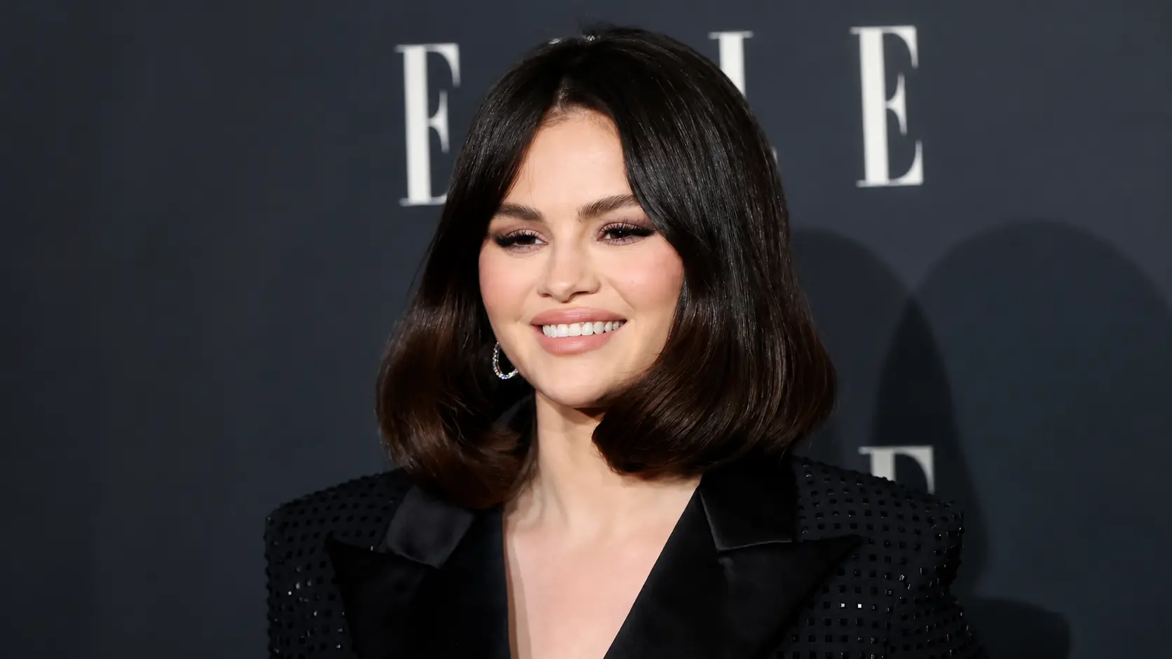 selena gomez with a sleek black bob haircut and elegant makeup wearing a black outfit at a formal event.