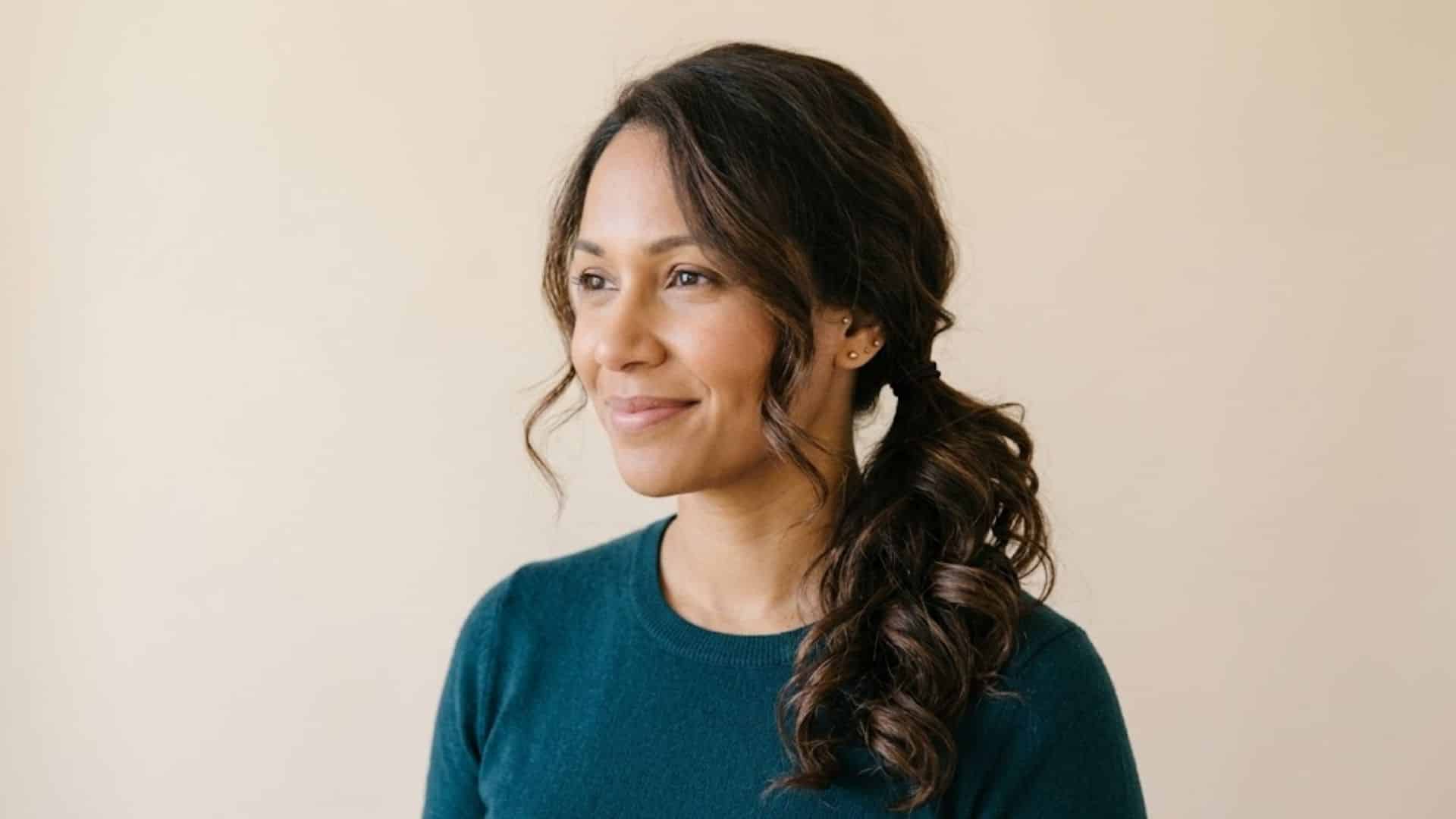 Woman with curly dark hair styled in a low side ponytail