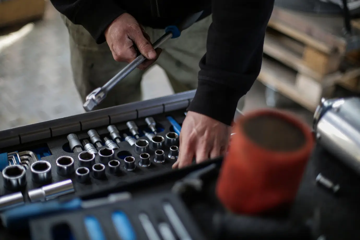 Mechanic selecting socket wrench from organized toolkit in workshop setting