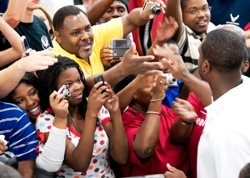 Enthusiastic crowd taking photos and reaching out in a lively indoor setting