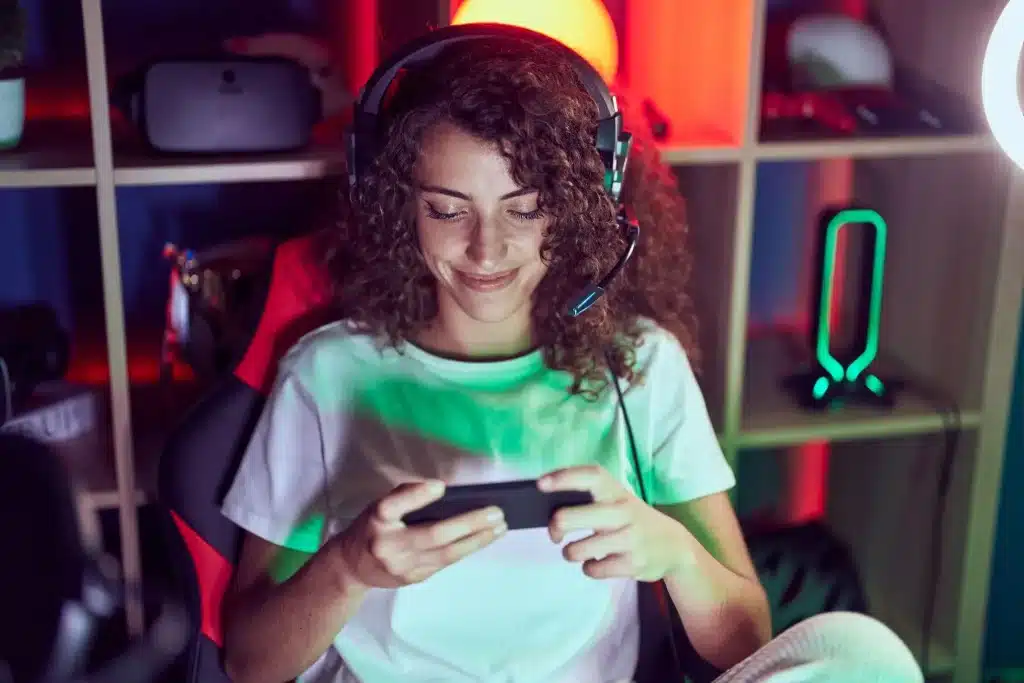 Woman enjoying mobile gaming with headphones in a colorful gaming room