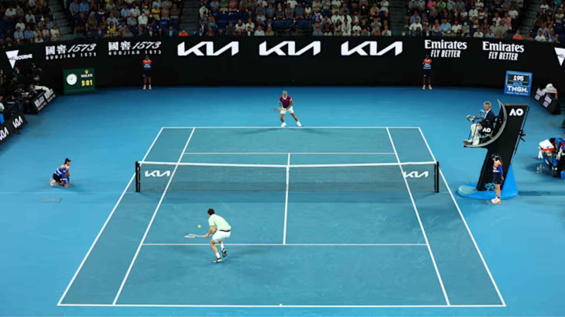 Professional tennis players compete in a hard-court match inside a packed stadium during a major tournament.