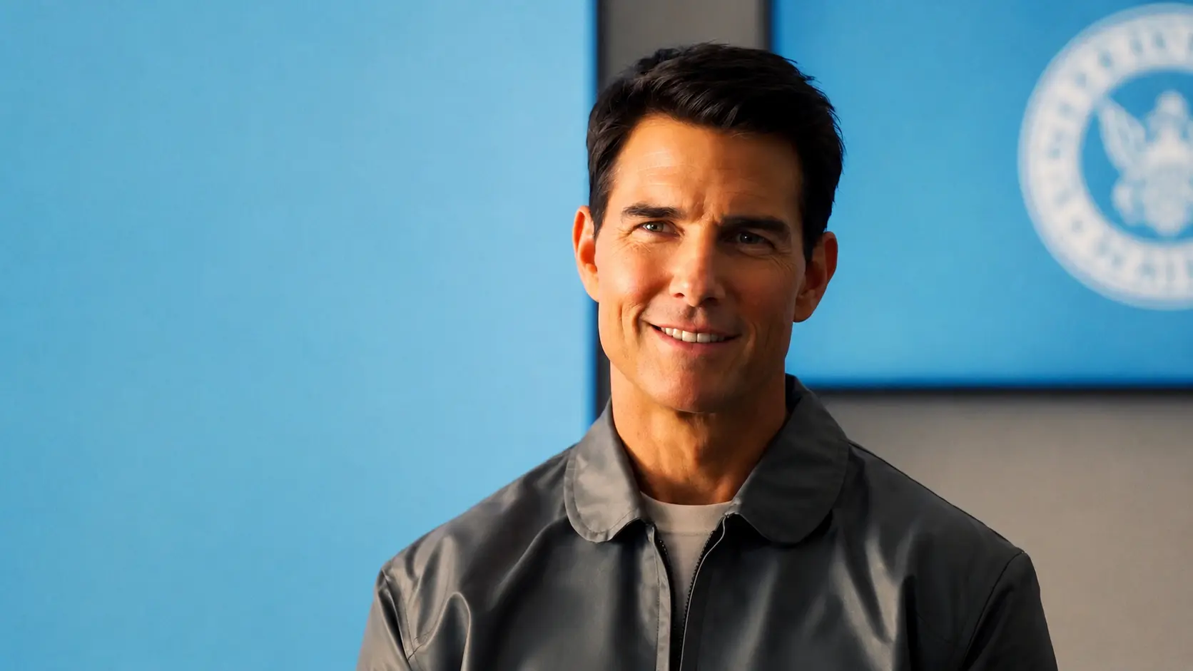 Tom cruise with short dark hair wearing a gray jacket posing against a blue and gray modern background