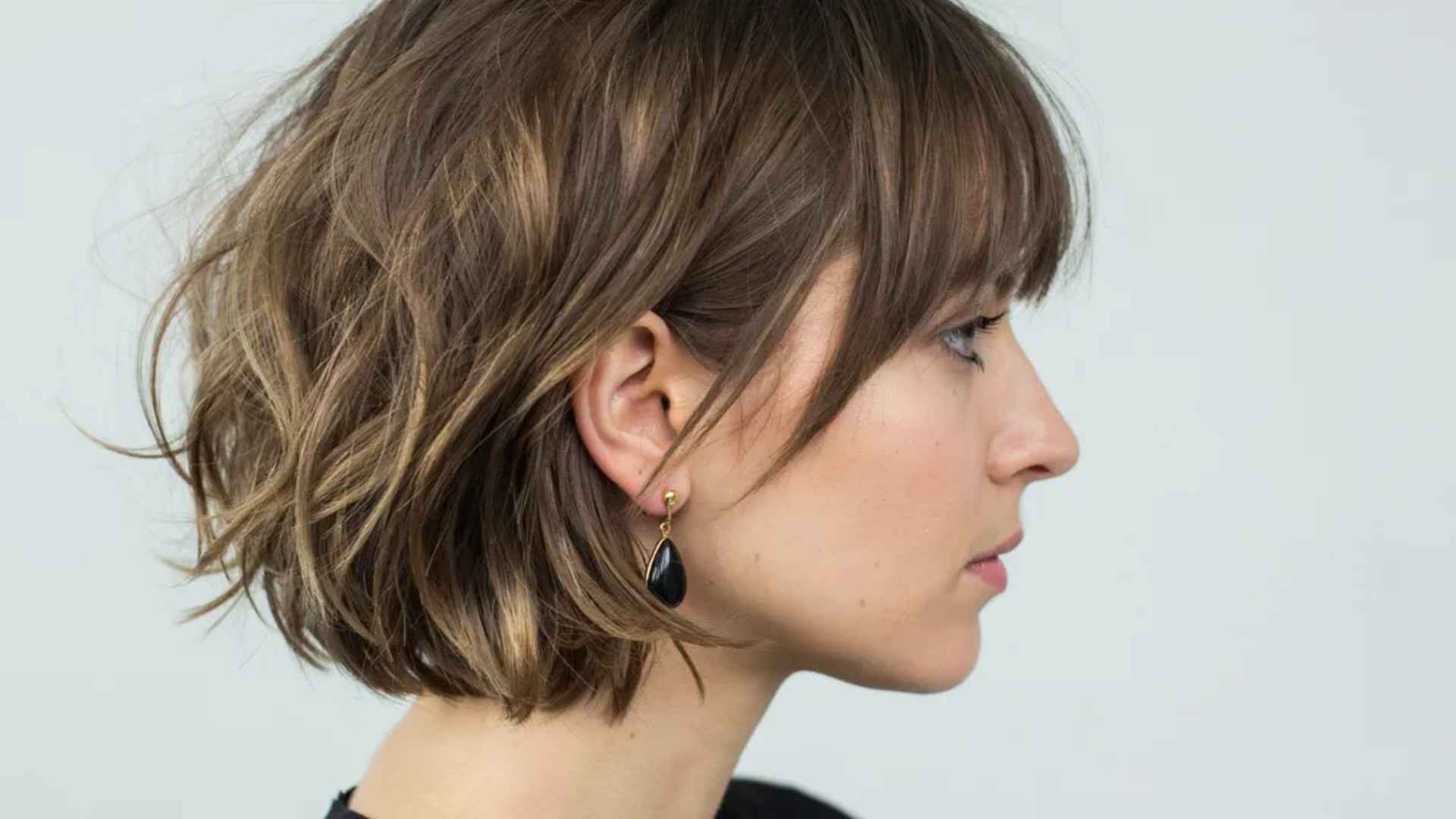 Woman with volumizing layered bob featuring crown lift and root volume creating bouncy full textured hairstyle