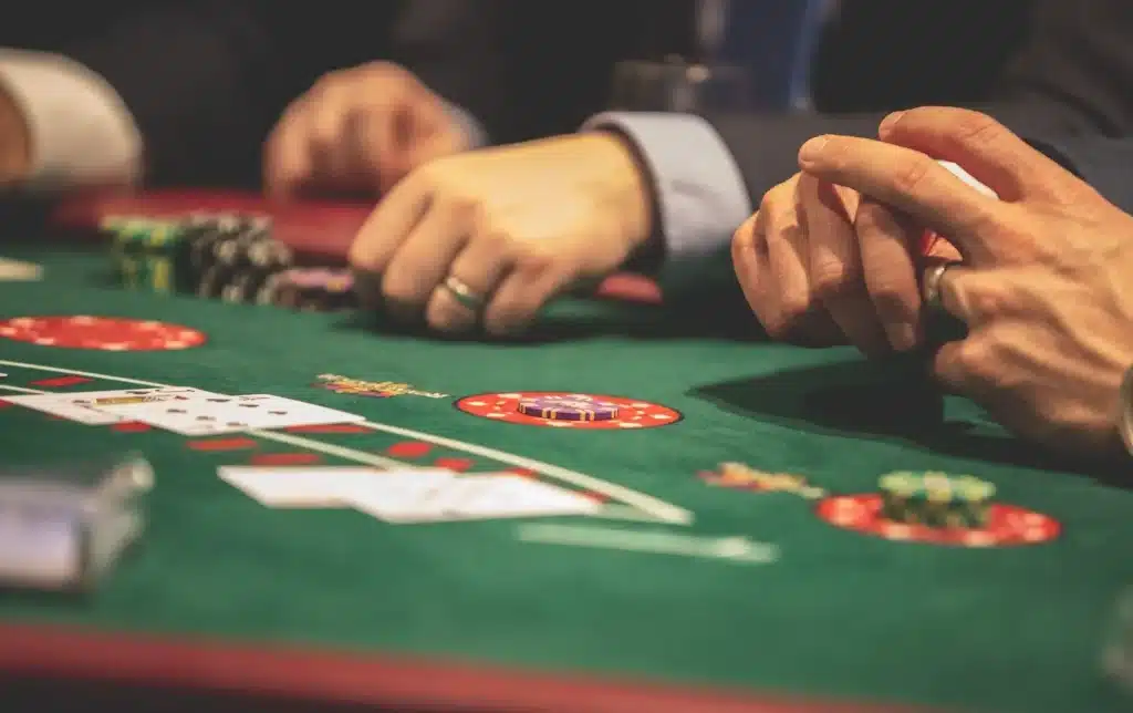 Hands holding cards and poker chips on a green casino table