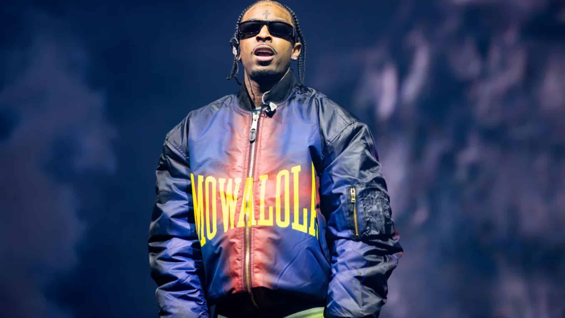 21 Savage performing on stage during a live concert wearing sunglasses and a jacket