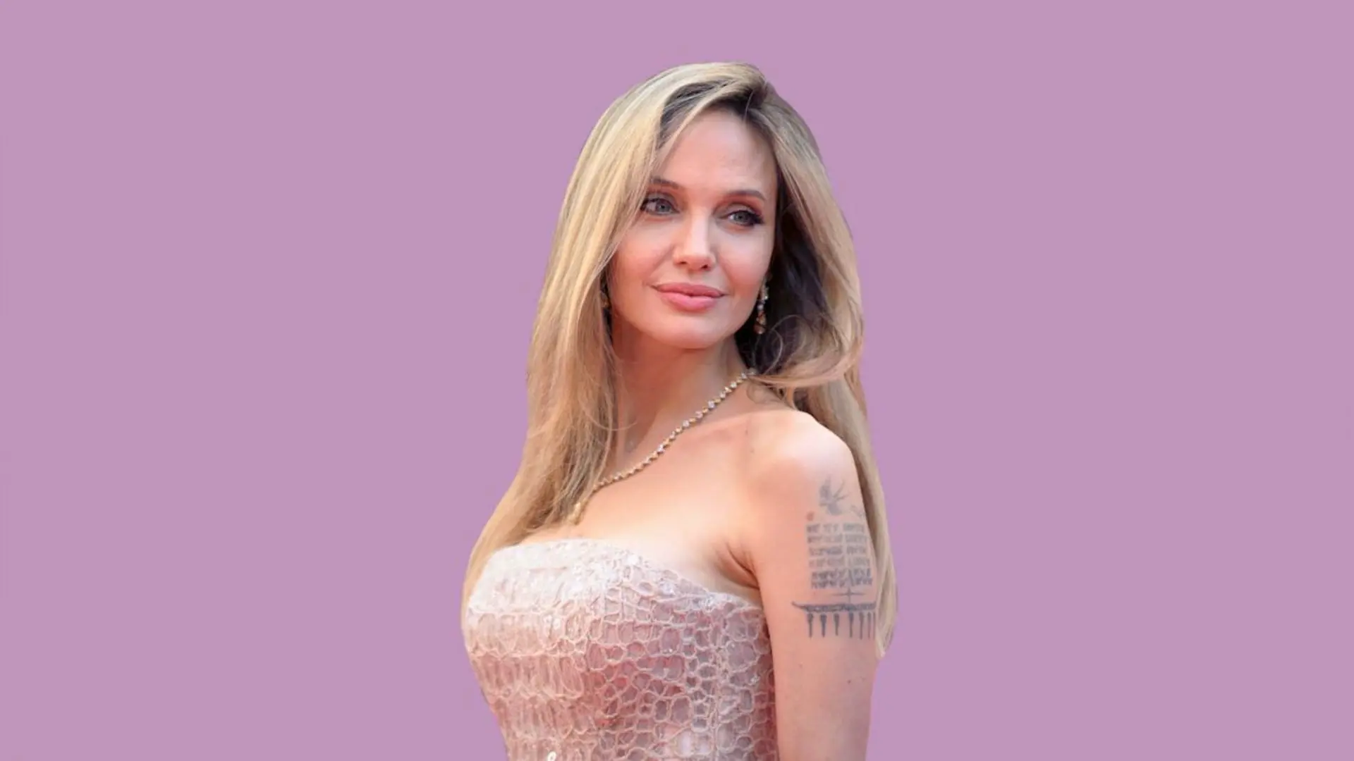 Angelina Jolie with blonde hair wearing a white lace dress and necklace posing against a soft purple background at an event