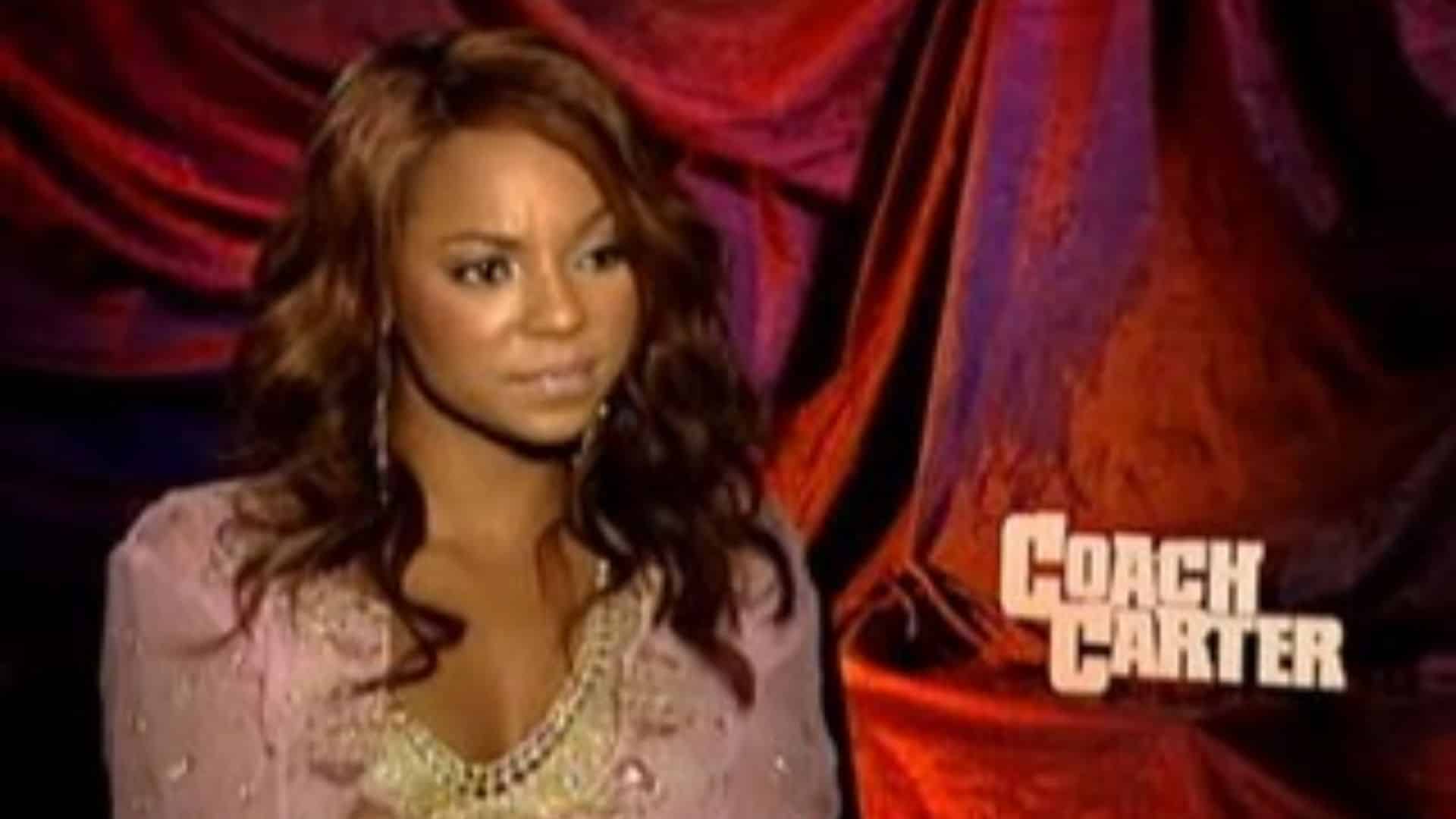 Ashanti appearing in a Coach Carter promotional scene wearing a pink outfit with a movie backdrop behind her