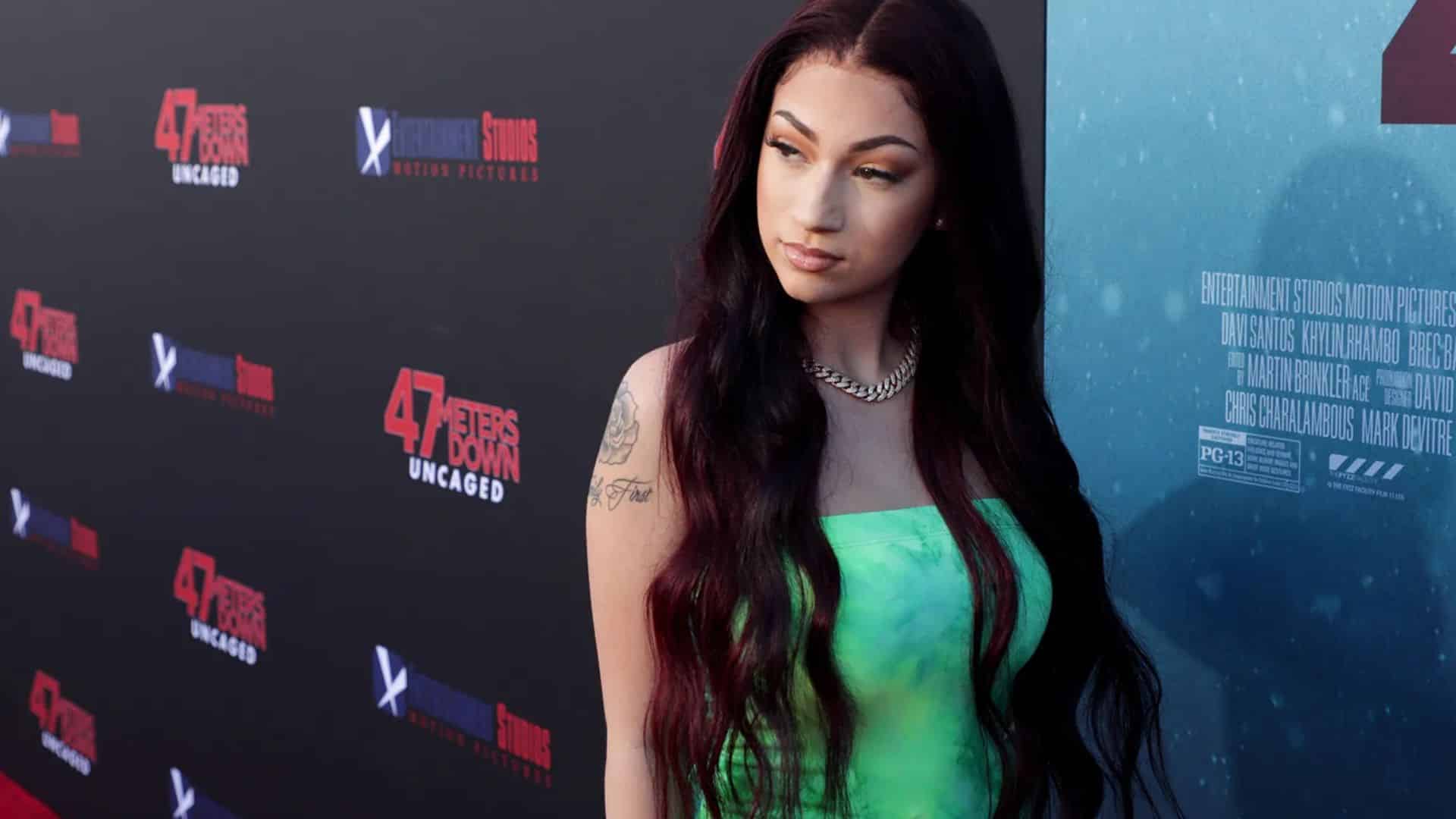 Bhad Bhabie photo showing a woman in a bright green dress posing on the red carpet at a movie event.