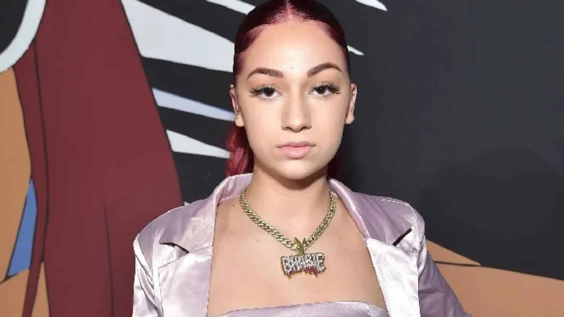 Bhad Bhabie photo showing a woman with red hair wearing a satin outfit and statement necklace.