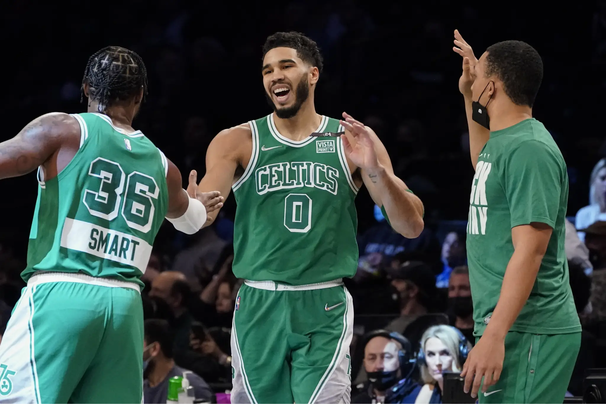 Basketball players in green jerseys celebrating during a game on court