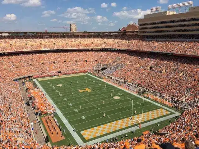 Crowded football stadium with game in progress under clear sky