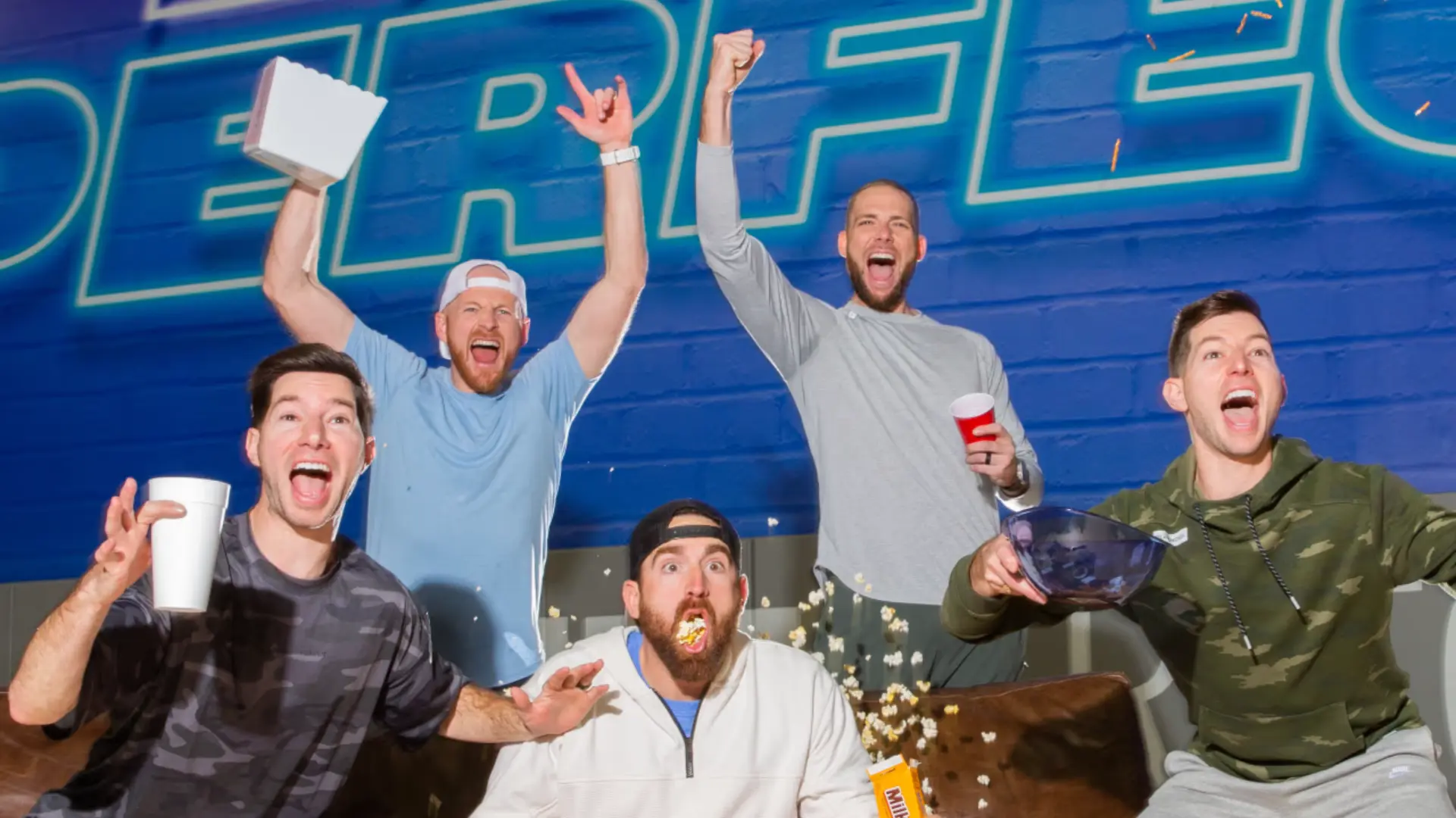 Dude Perfect YouTube group members celebrating together in front of a blue backdrop