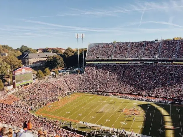 Football stadium filled with cheering fans under clear sky during daytime game