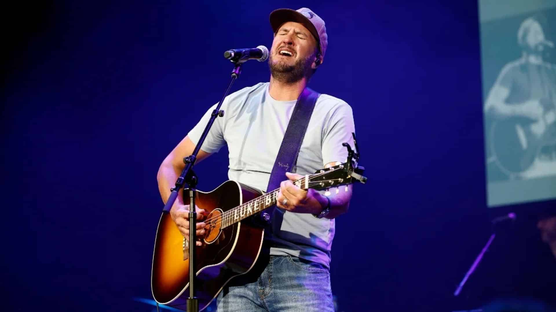 Luke Bryan playing guitar and performing his songs live on stage.