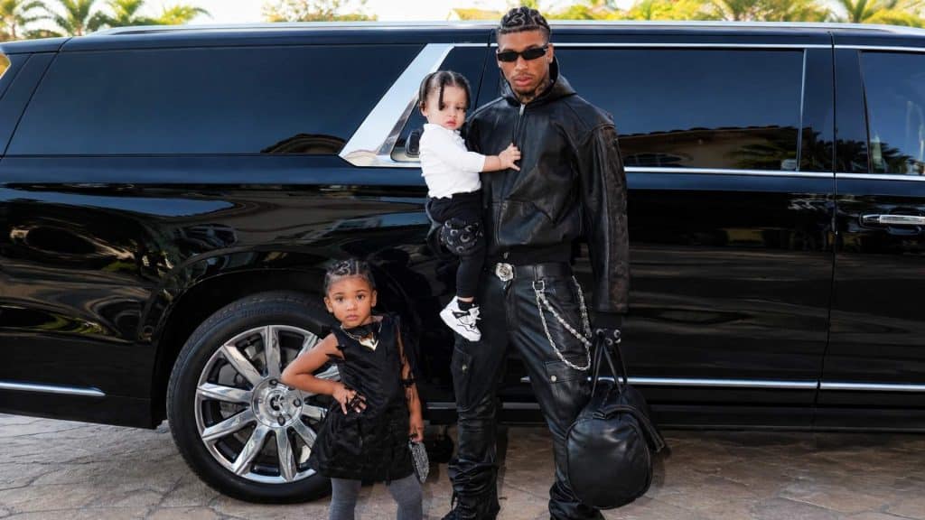 NLE Choppa posing with his children beside a black luxury SUV during an outdoor family moment.