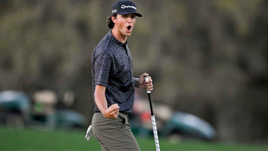 Grant Horvat wearing TaylorMade cap and patterned shirt celebrates on the course while holding a club during a competitive moment