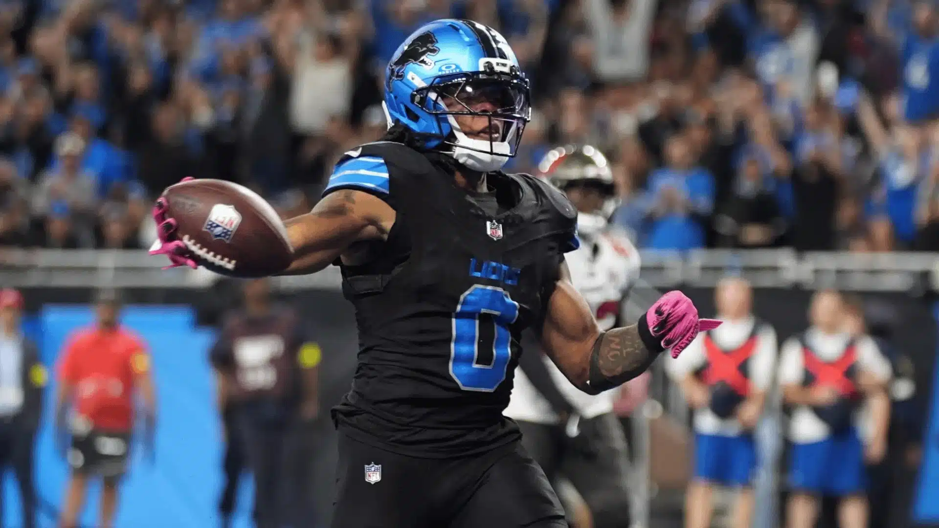 Jahmyr Gibbs holds out the football while celebrating on the field