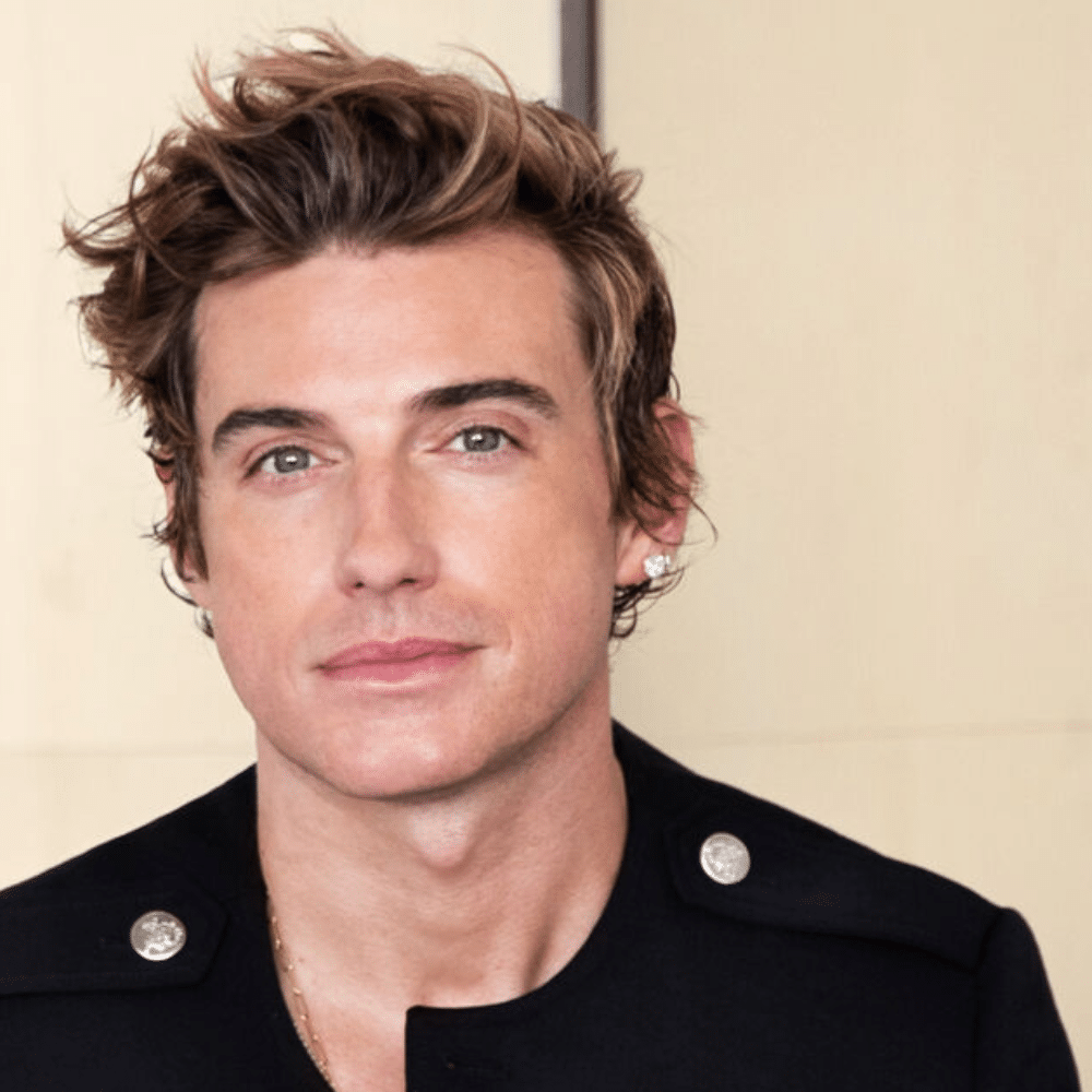 Portrait of Jeremiah Brent with styled hair wearing black jacket with silver buttons against neutral background.