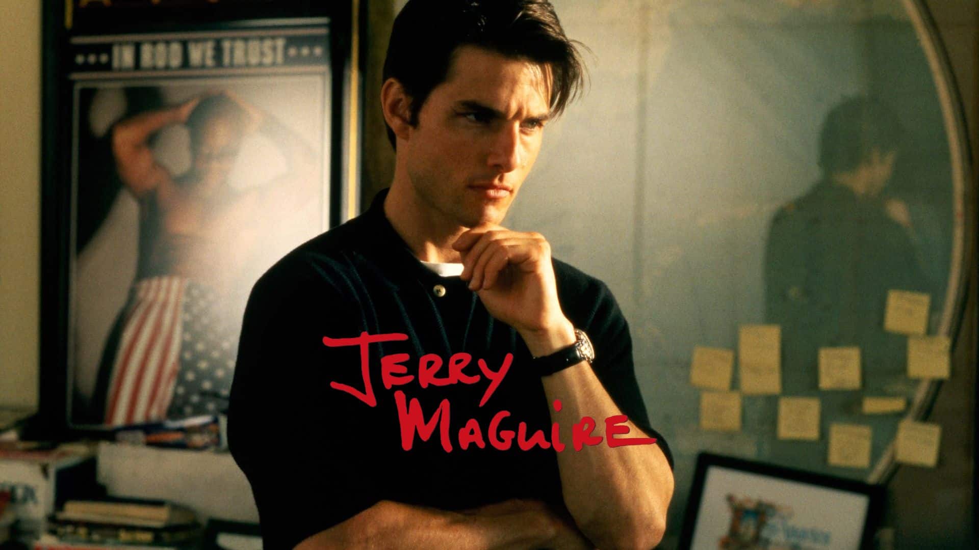 Man in dark polo shirt in office with sticky notes and posters,