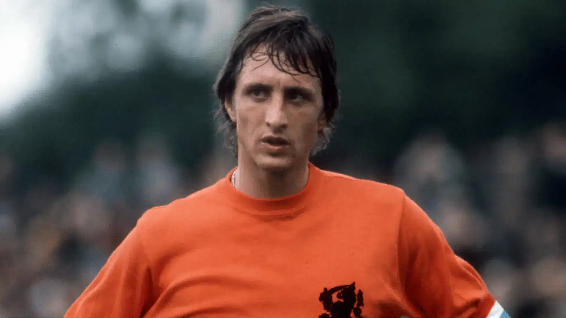 Johan Cruyff wearing the Netherlands jersey and captain’s armband during a soccer match.