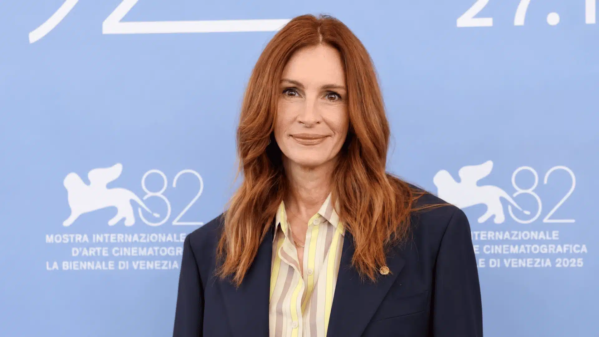Julia Roberts smiling with long auburn hair, wearing a dark blazer at the Venice Film Festival 2025