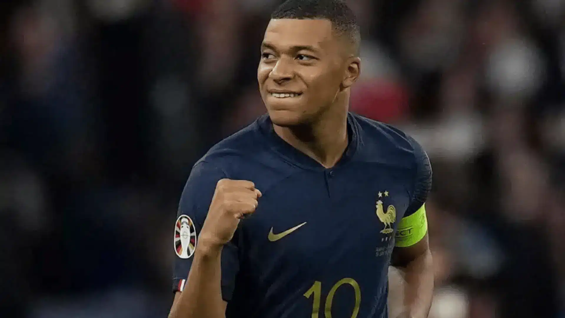 Kylian Mbappé celebrates with a raised fist while wearing France’s number 10 soccer jersey and captain’s armband.