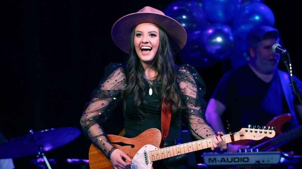 Maggie Baugh performing live on stage with her guitar