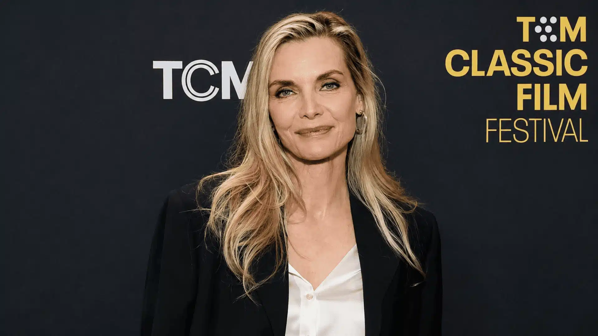 Michelle Pfeiffer posing at the TCM Classic Film Festival in a black blazer with long blonde hair