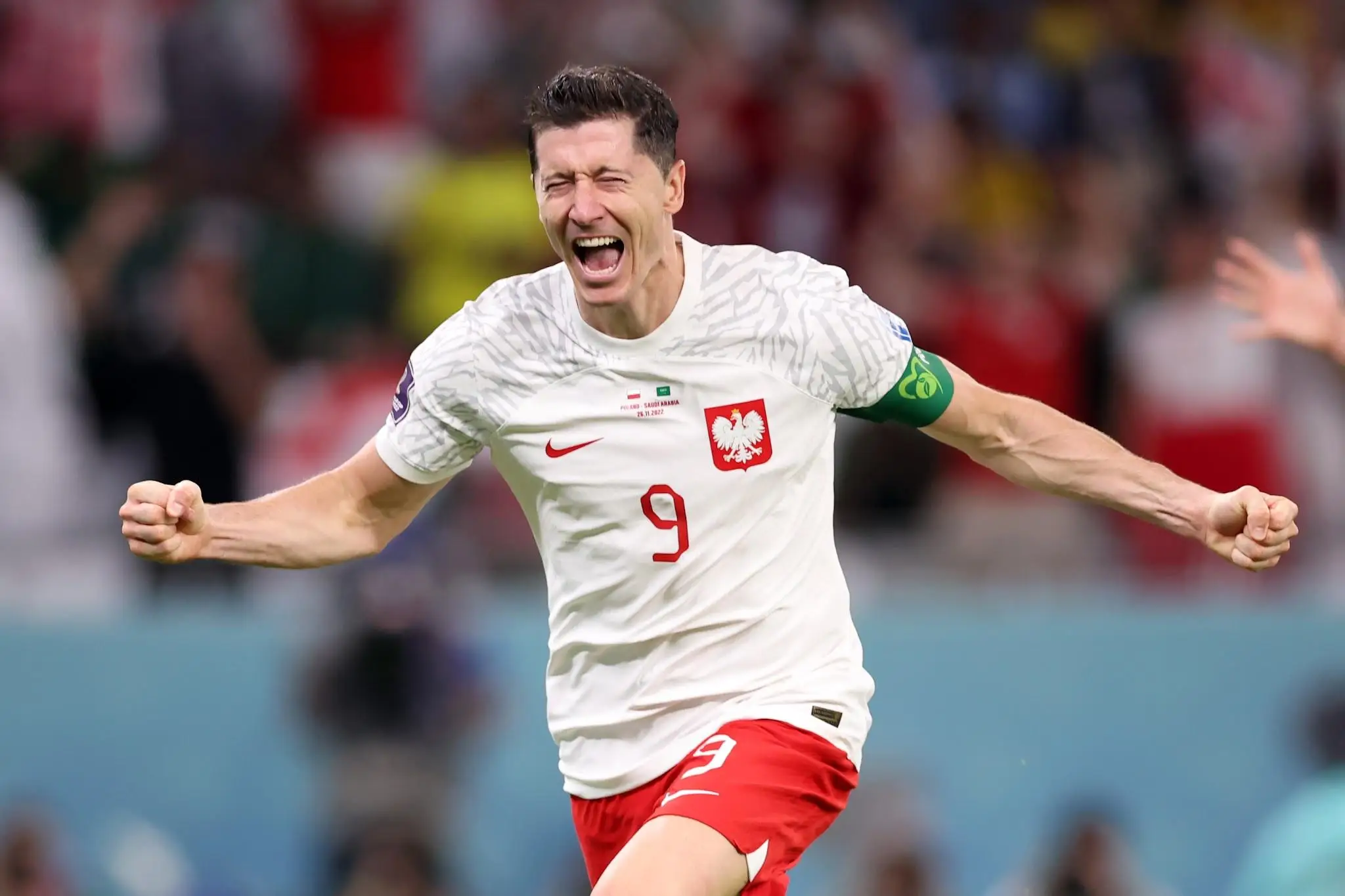 Soccer player in white jersey celebrating on field with arms outstretched