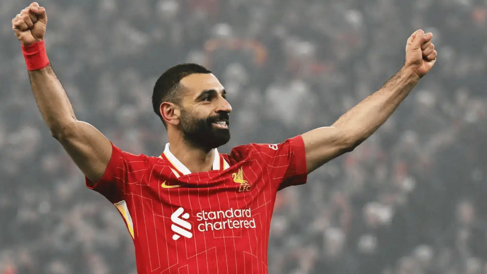 Mohamed Salah celebrates with both arms raised while wearing Liverpool’s red soccer jersey.