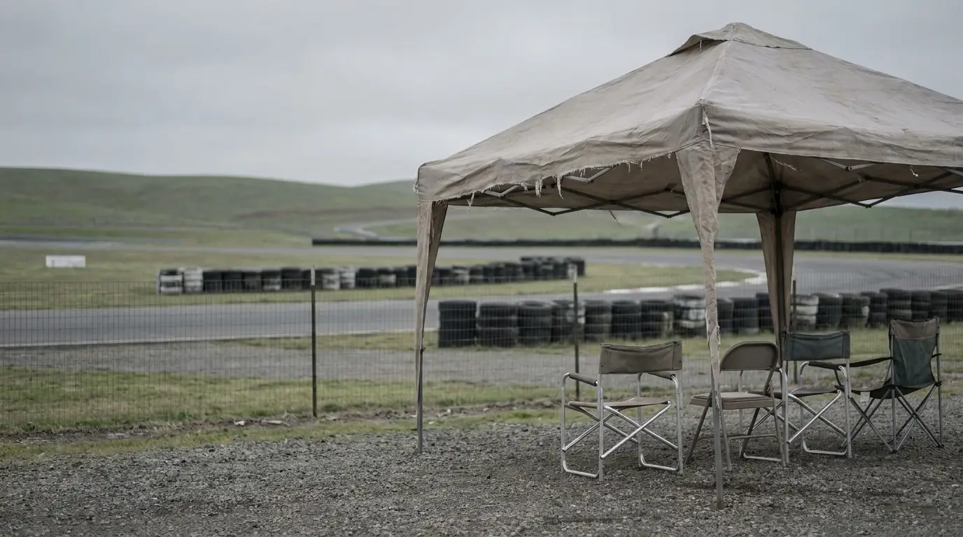 Canvas canopy with folding chairs overlooking a racetrack in a rural setting on a cloudy day