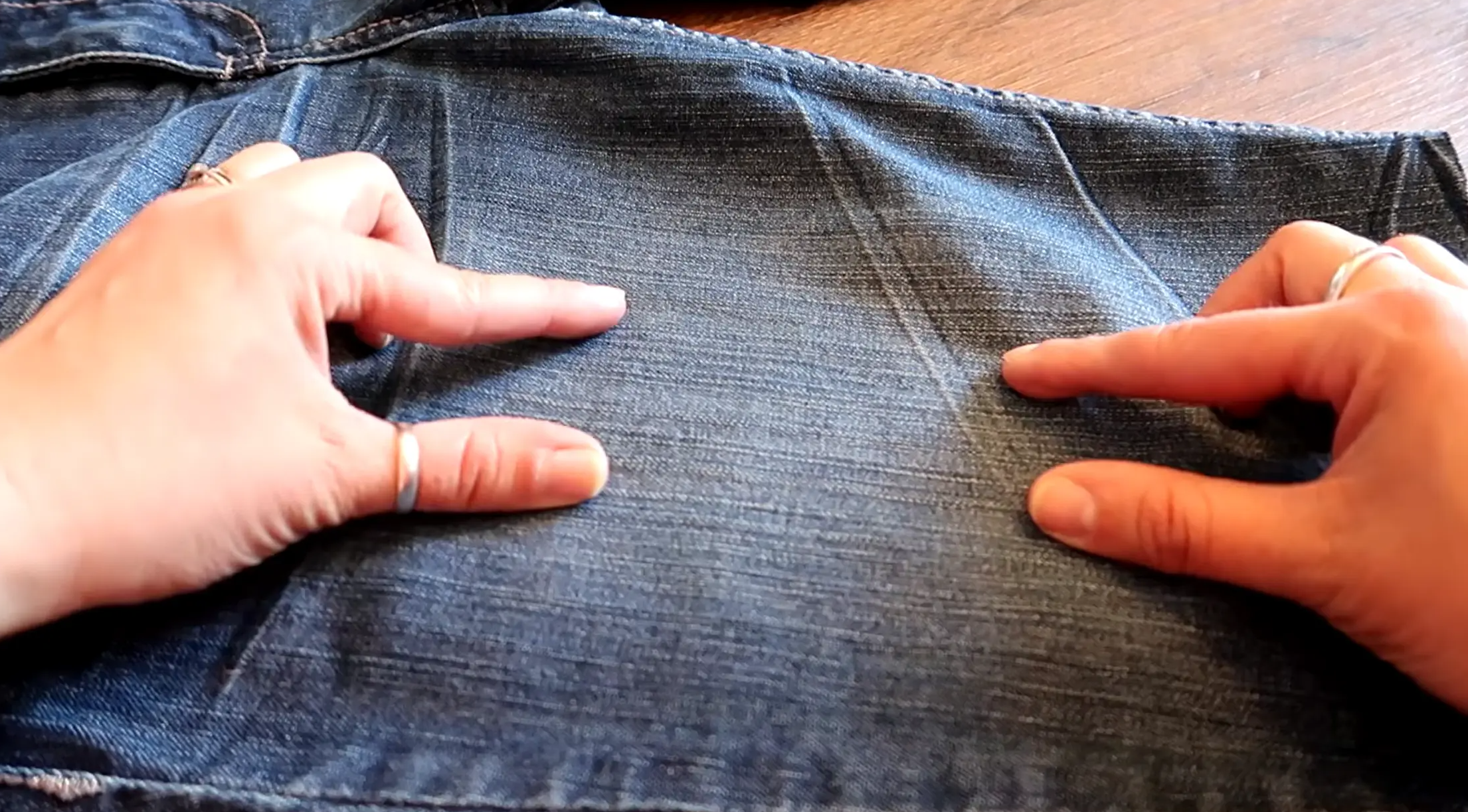 Person marking the area on jeans where a distressed cut will be added