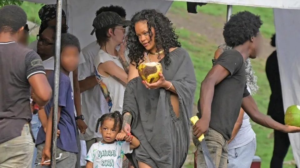 Rihanna during a family trip in her native Barbados, stopping at a roadside stand to share fresh coconut water and jelly with her children.