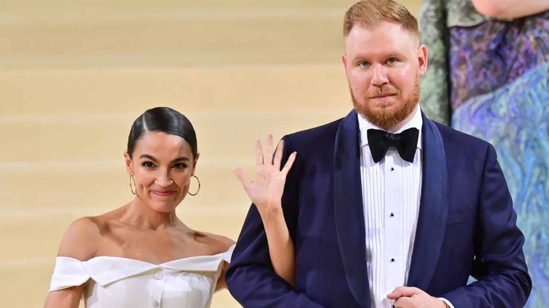 Riley Roberts and Alexandria Ocasio Cortez posing together in formal attire at a gala event with a softly blurred background