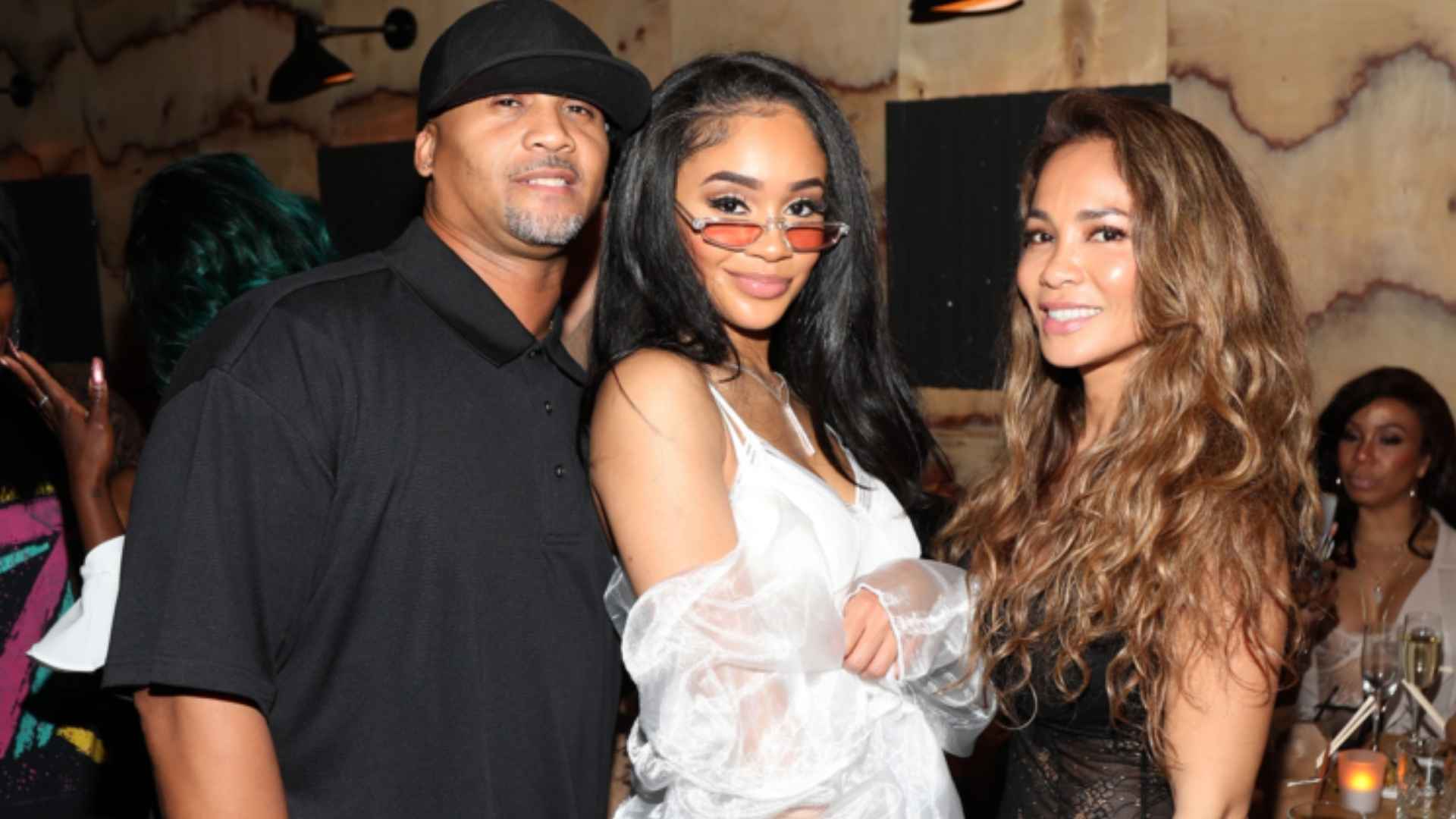 Saweetie posing with her parents at an event in a group photo