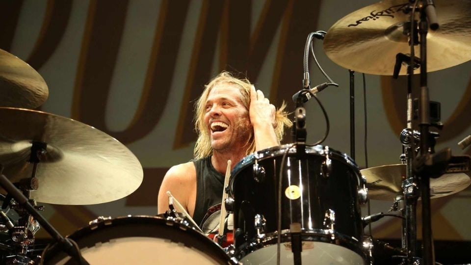 Taylor Hawkins, the longtime, high-energy drummer for the rock band Foo Fighters, smiling behind his drum kit during a live performance.