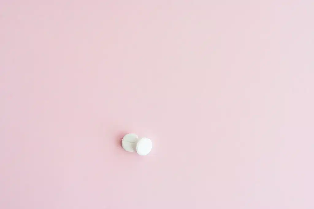 White pills on a soft pink background