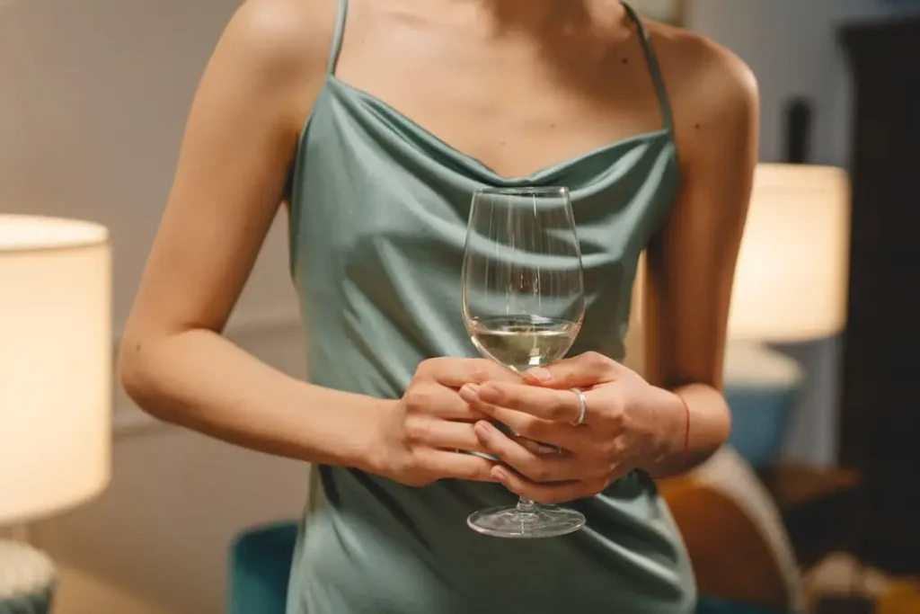 Woman in light blue dress holding wine glass in cozy indoor setting
