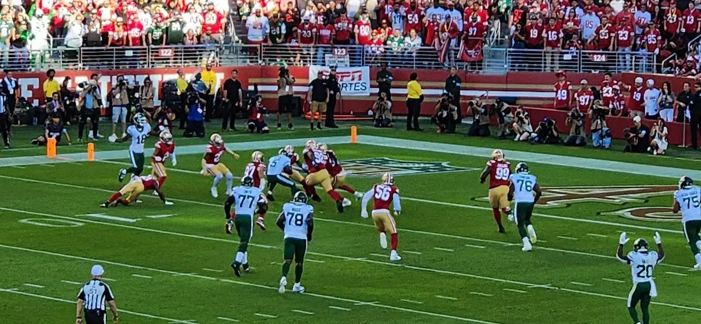 Football game with players in red and white uniforms tackling opponents on green field