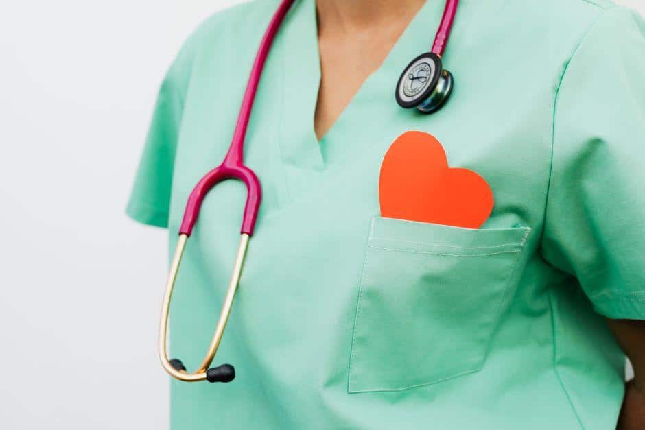 Medical professional in green scrubs with stethoscope and red heart in pocket